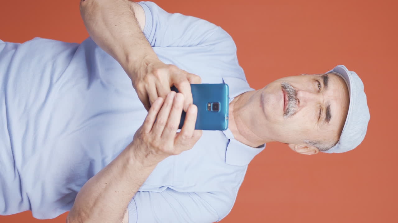 vídeo vertical de un anciano feliz enviando mensajes de texto por teléfono. sonriendo.