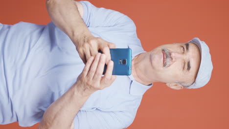 Vertical-video-of-Happy-old-man-texting-on-the-phone.-Smiling.