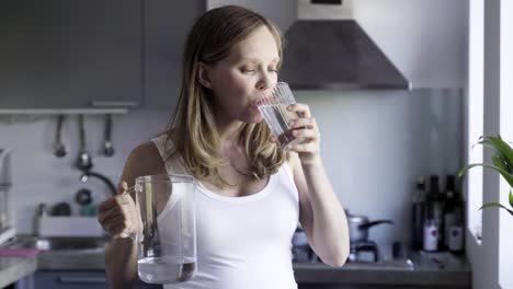 Calm-beautiful-woman-pouring-and-drinking-water