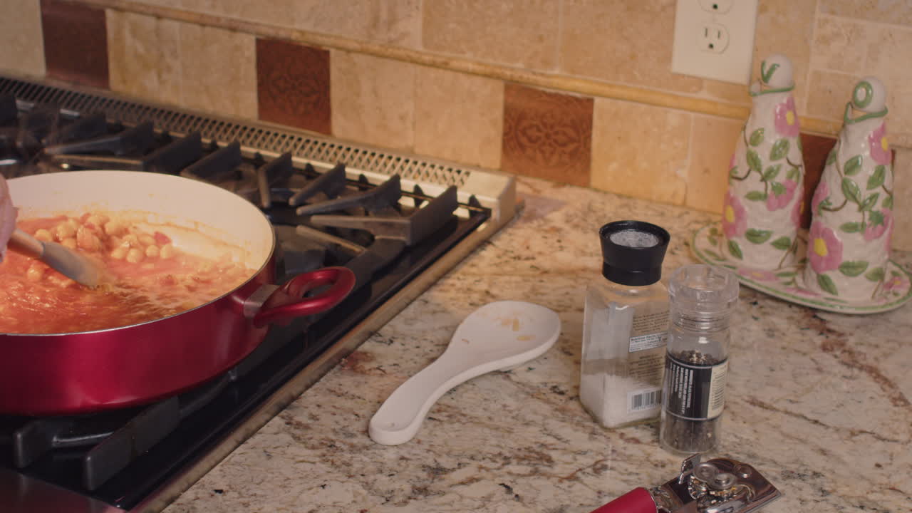 Woman cooking a chick pea dish on the stove and using a spoon to stir