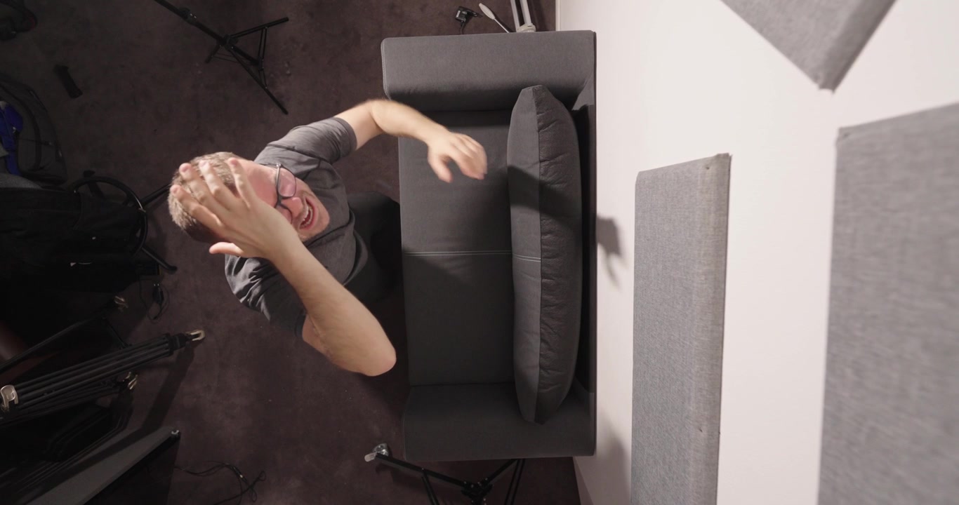Overhead slow-motion view of a man rotating and changing position while sitting in an armchair. Indoor lifestyle, relaxation, movement, and home living concept.