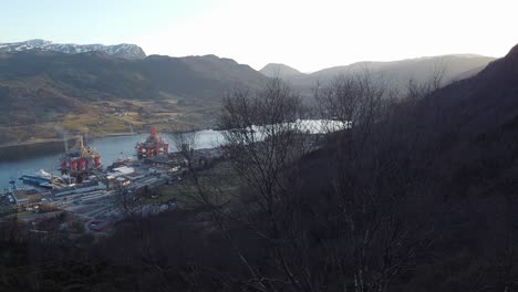 Sideways-moving-aerial-showing-Olensvaag-Norway-and-drilling-rigs-at-Westcon-yards-shipyard---sideways-moving-aerial-at-dawn