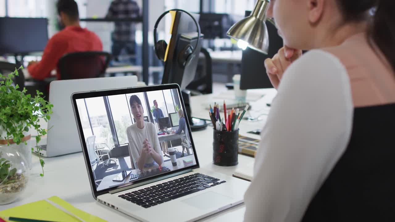 Kaukasisk kvinde der har et videomøde med en kvindelig kollega på sin laptop på kontoret.