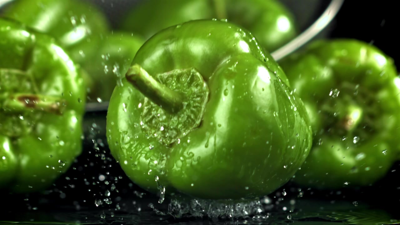 Slowmotion van een groene paprika die in het water valt.