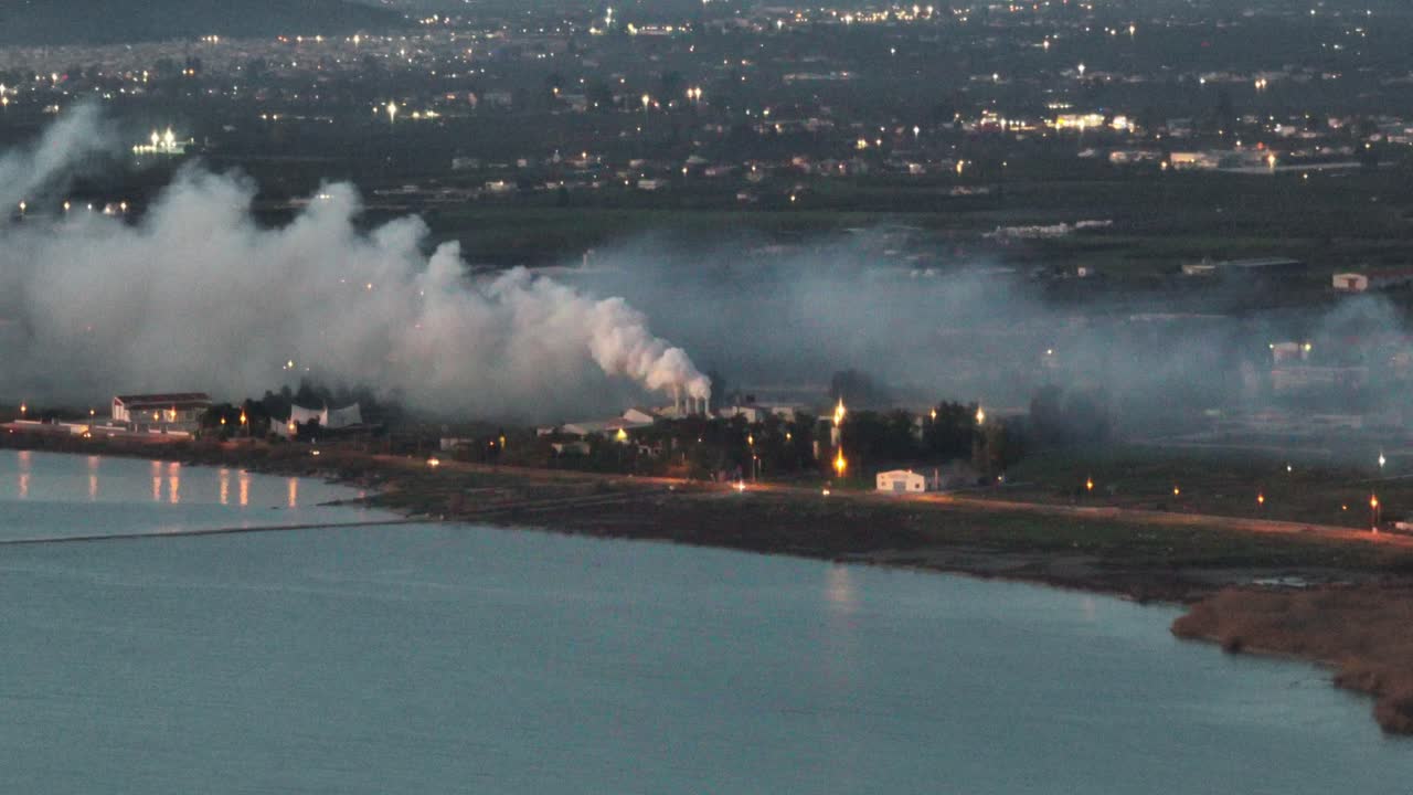 Aerial footage of dense smoke from a factory next to the sea