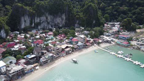 aerial view : pier and beachfront port of el nido town proper ahead of lush tropical background of towering limestone rocks, bacuit bay - philippines