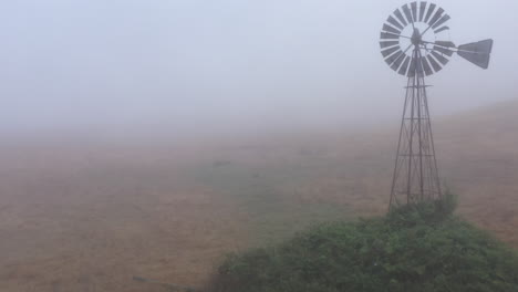 sobrevuelo aéreo con revelación de inclinación de un antiguo molino de viento en una densa niebla