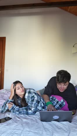 pareja relajándose en el dormitorio con una computadora portátil