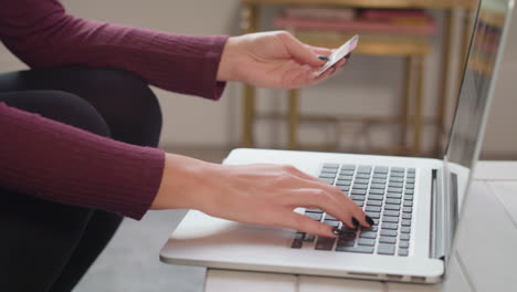 captura de pantalla en cámara lenta de una joven que usa una laptop para hacer una compra en línea, celebra con un golpe de puño cuando completa la compra