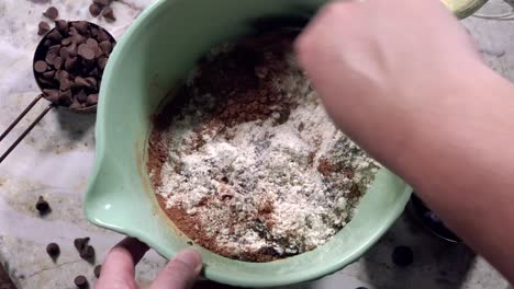 por encima de la cabeza revolviendo los ingredientes de la masa seca en un tazón grande para mezclar