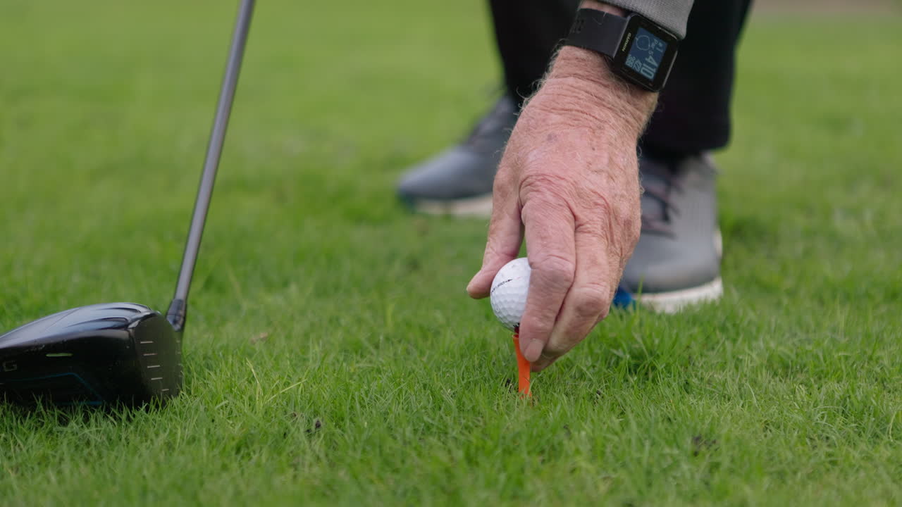 Close-up of a golfer placing a golf ball on a tee