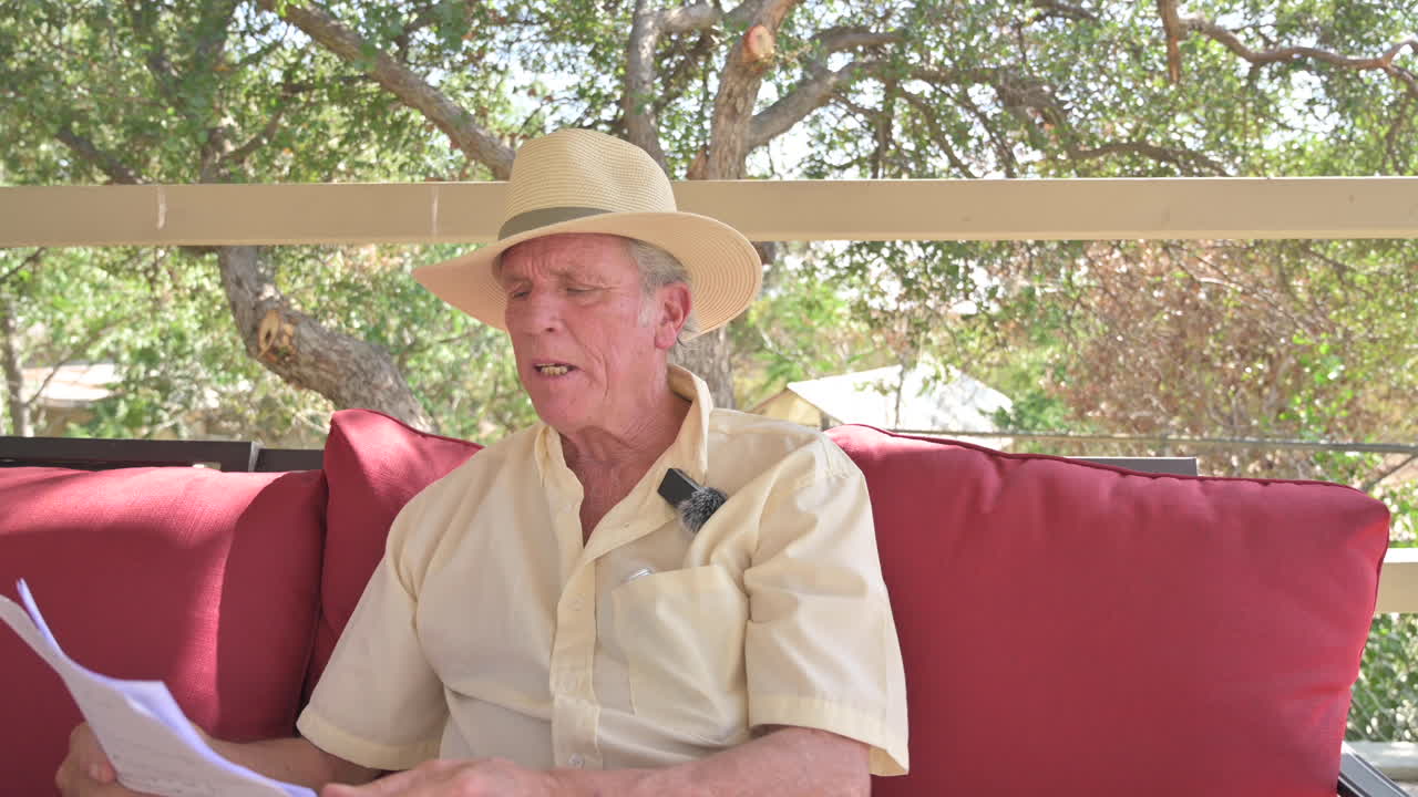 카메라 밖의 사람과 토론을 하고 대본을 손에 들고 활기찬 몸짓을 하는 잘생긴 노인