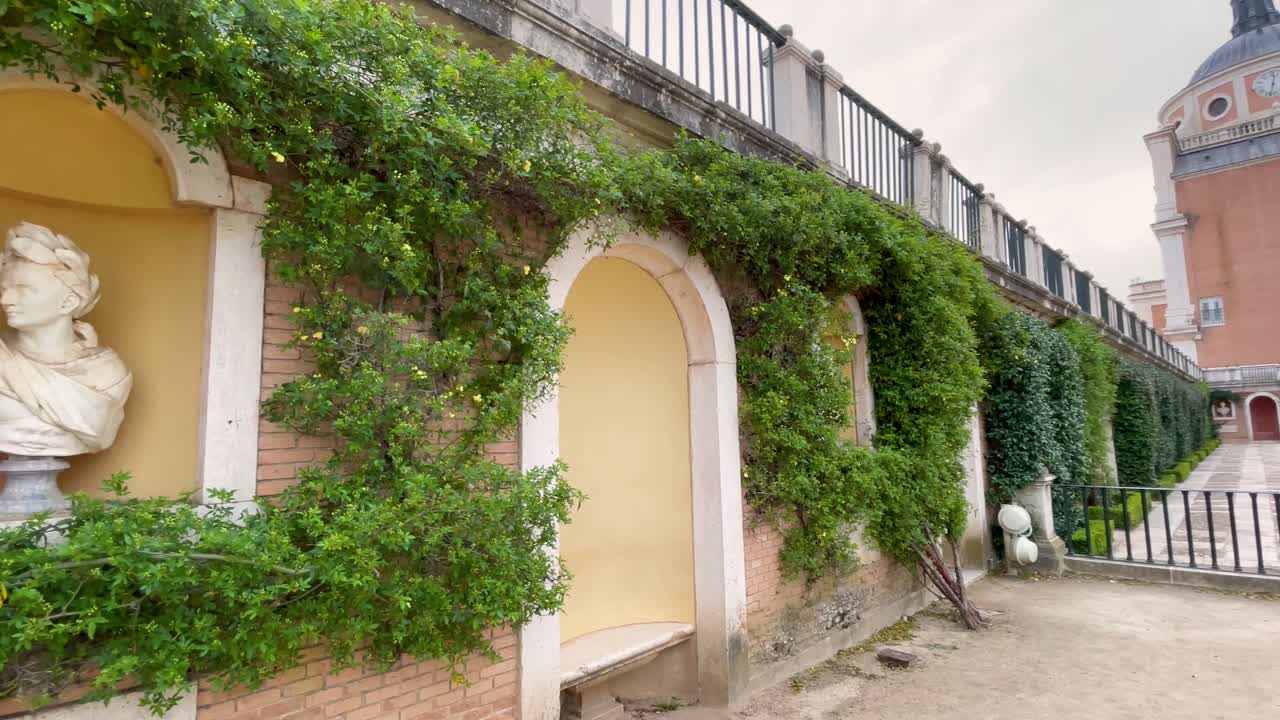 Filming of a rear part of the Royal Palace of Aranjuez where a wall appears with a sculpture of a Caesar belonging to the King's Garden with a camera pan showing the palace and its immense dome