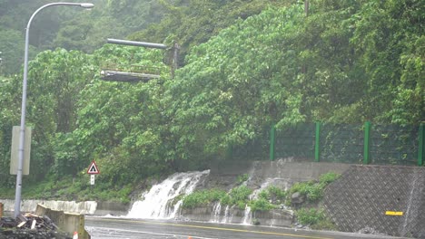 typhoon approaching, bad visibility and dangerous driving condition with heavy rainfall that developed a little falls on the roadside at hsuehshan tunnel at hualien city, taiwan