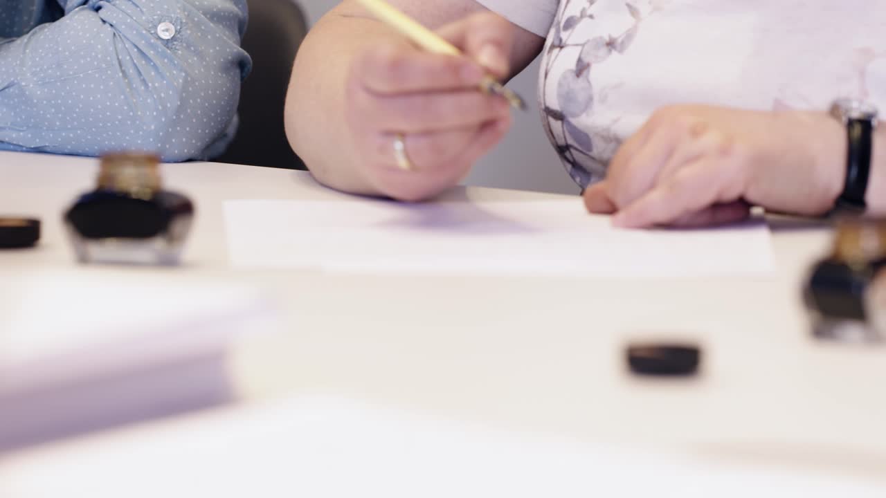 female hand writting oldschool black ink pen on the white sheet of paper close  up slow motion in focus ine  class room