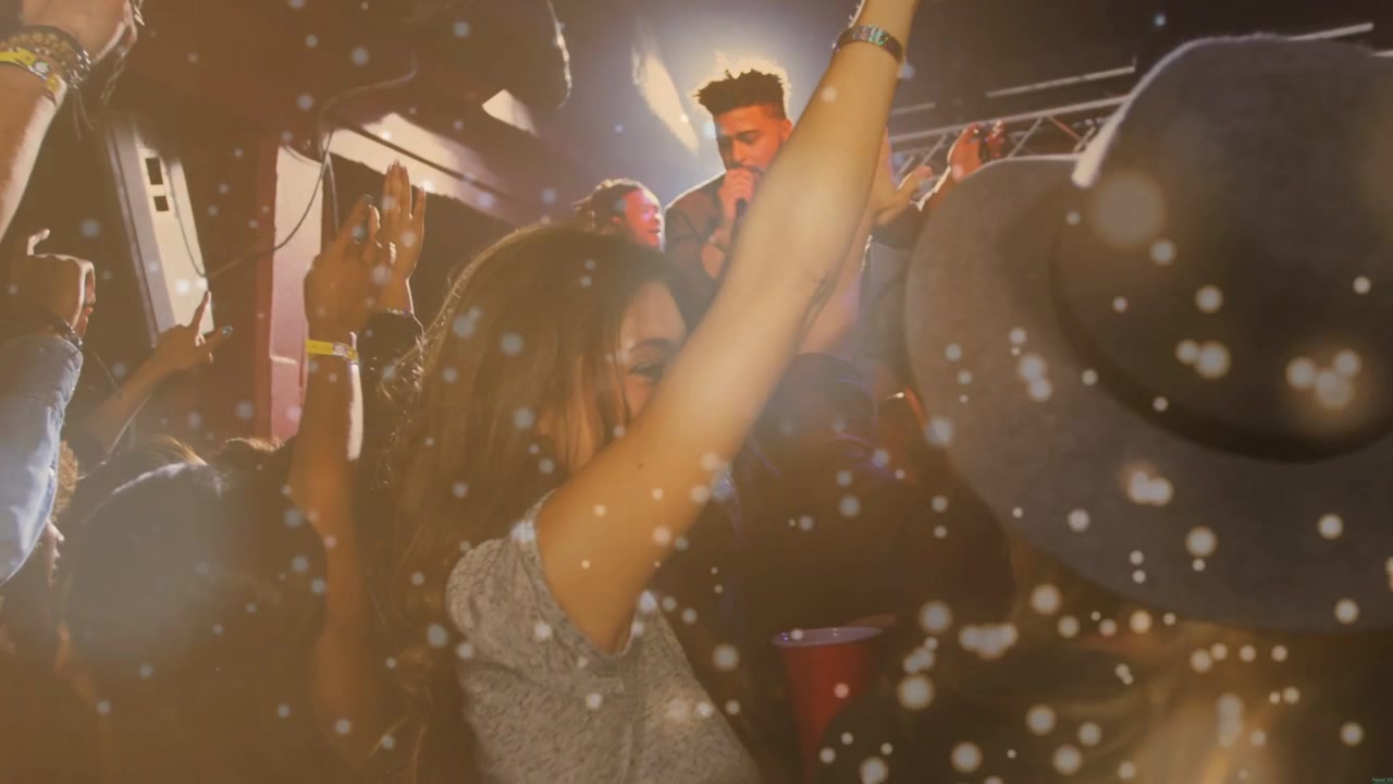 Singer starting song into mic under stage lights, front woman raising right arm, confetti floating