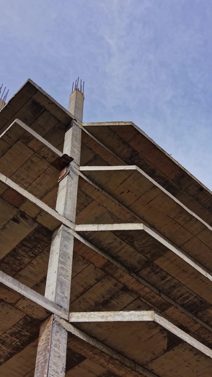 Aerial view of an unfinished concrete building structure under blue sky