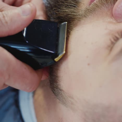 close up of barber shaping client's beard