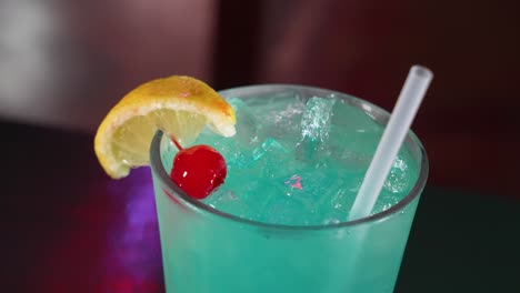 un cóctel azul helado adornado con una rodaja de limón y una cereza marraquino, cerca de 4k