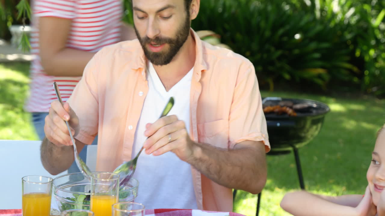 retrato de un padre feliz comiendo con su familia en el jardín