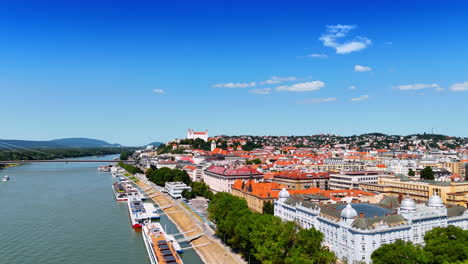 flying over the old bridge over the danube and old town in the city. aerial view on the historical part of bratislava, slovakia on sunny day