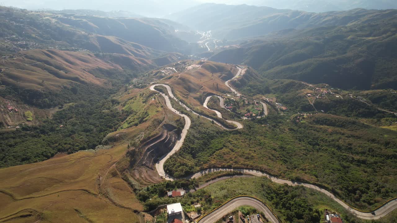 Winding road through lush mountain landscape, aerial view capturing natural curves