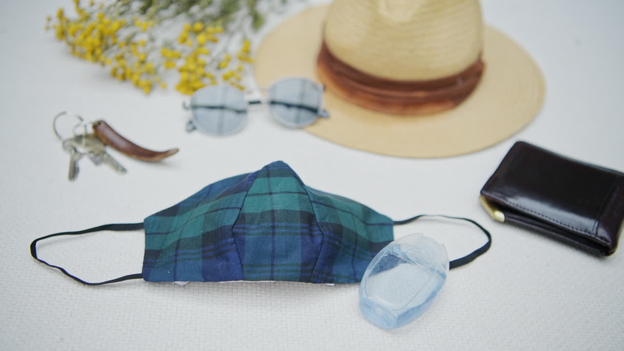 A slow pan of personal items including a face mask, hand sanitizer, keys, hat and wallet