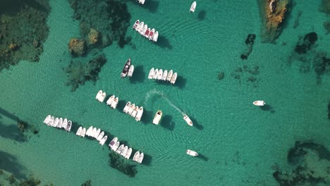 bird's eye view of turquoise green crystal clear ocean water with small boats anchored in corfu greece