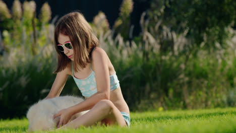 a child plays with a puppy in the backyard of the house. sitting on a manicured lawn