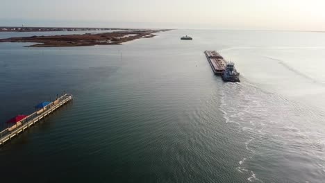 aerial view of two large barges motoring along the gulf intracoastal waterway in laguna madre near sunset