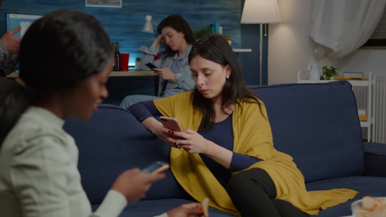 amigos multirraciales relajándose en el sofá mientras navegan por las noticias en internet usando el móvil