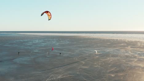 beautiful drone shot of kite boarding over frozen sea in a sunny day