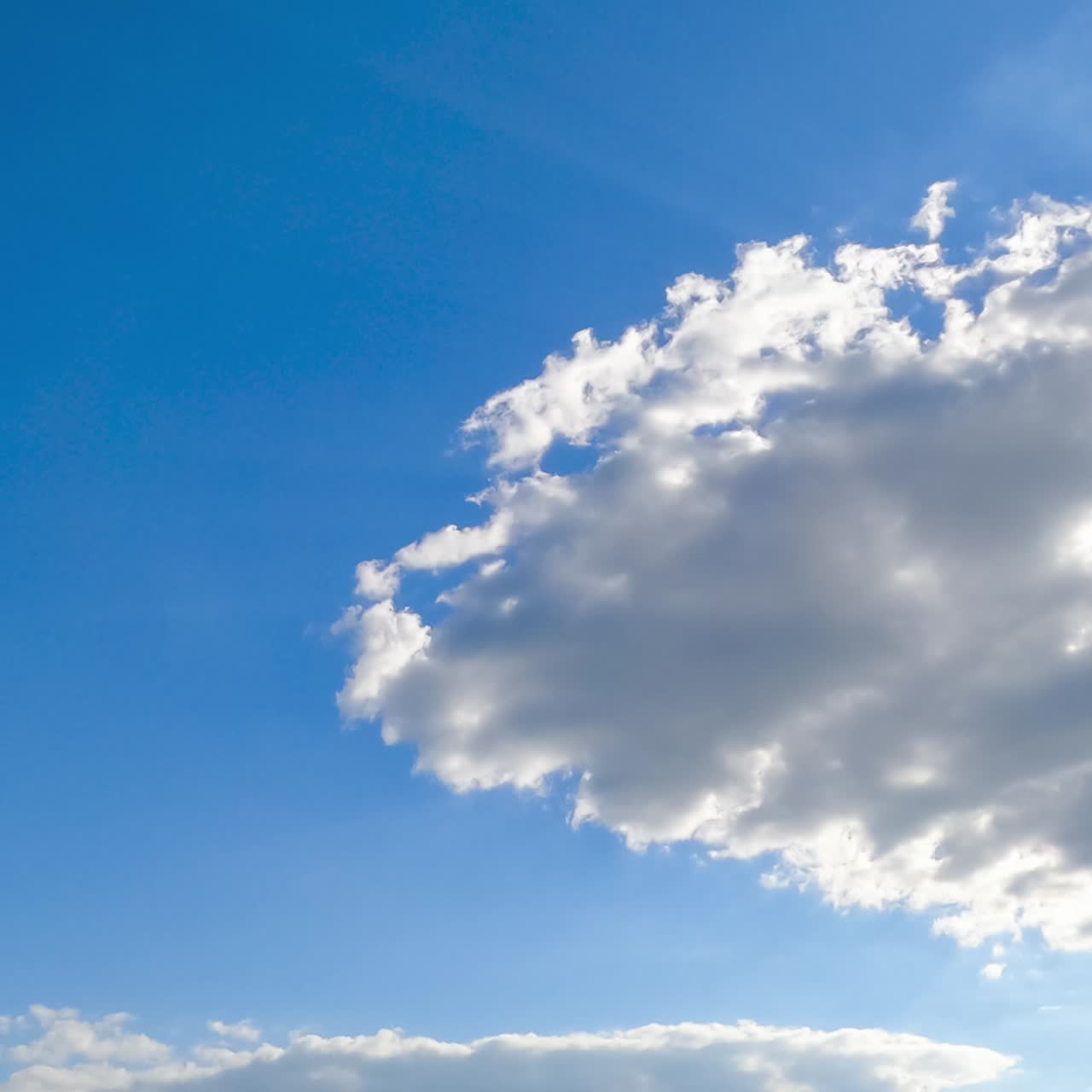 Summer sun shining on the white clouds. Beautiful cotton clouds flying quickly in the sunrays. Timelapse