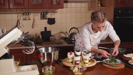 woman making a layered fruit dessert in a kitchen