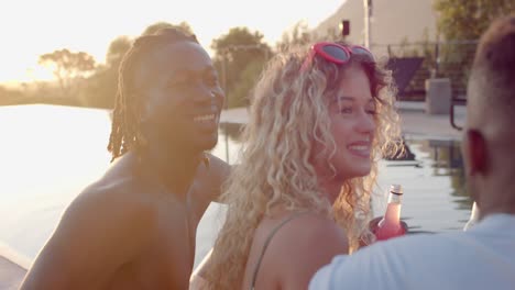 Happy-diverse-friends-with-drinks-talking-at-pool-in-slow-motion