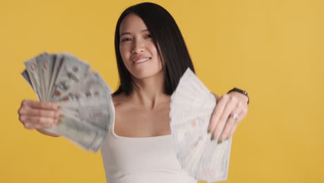 asian woman looking happy while holding money on camera.