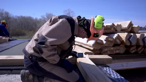 construction worker measuring wooden beams for house building