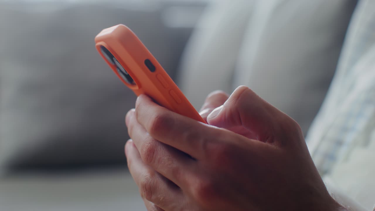 persona que utiliza un teléfono inteligente naranja