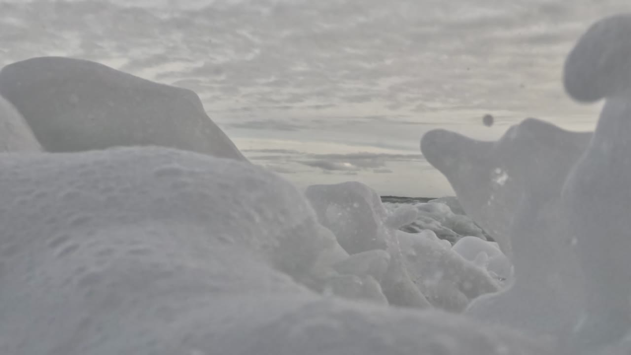 Close-up view of ocean waves creating foamy splashes under a cloudy sky.