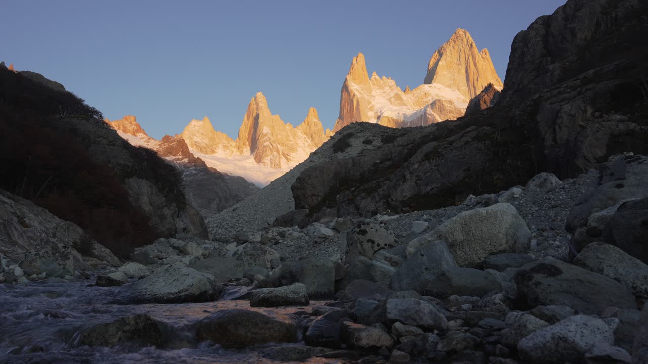 Catena montuosa patagonica illuminata all'alba e un fiume naturale che scorre nella valle
