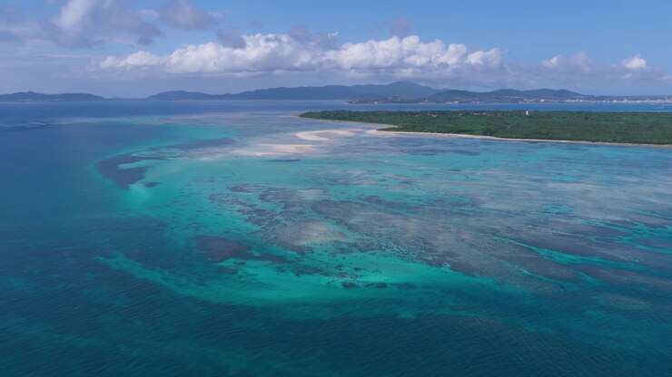 Riprese aeree orizzontali con panoramica a sinistra e carrello a destra sopra le barriere coralline e la laguna turchese di Kondoi Beach e Kaiji Beach, Isola di Taketomi, Okinawa, Giappone.