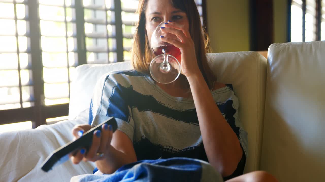 Woman having red wine while watching television 4k