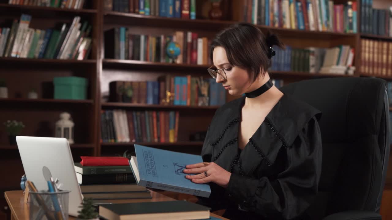 la chica está sentada en la mesa con muchos libros en ella