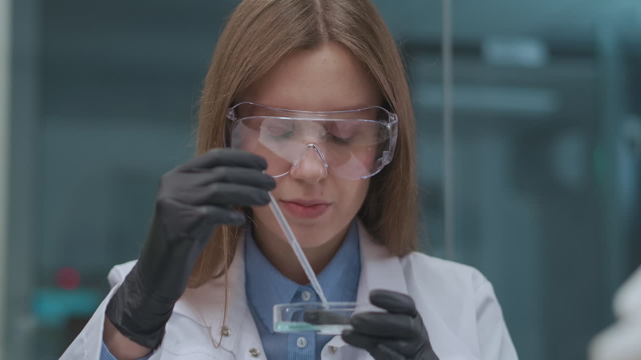 estudiante del instituto de química está haciendo un trabajo práctico en clase retrato de una mujer joven con gafas de protección guantes de goma y túnica blanca explorando reactivo