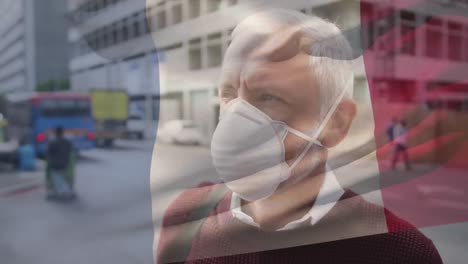 animation of flag of france waving over man wearing face mask during covid 19 pandemic