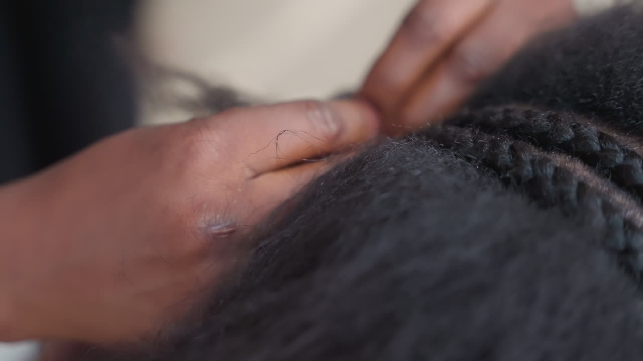 Lavoro di trecce dettagliato catturato perfettamente. Immagini ravvicinate di intricata arte delle treccine (cornrow) in corso. Cattura di dettagliati motivi del cuoio capelluto e abile tessitura dei capelli in un ambiente di studio professionale.