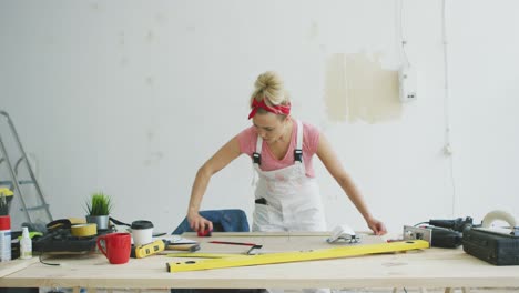 Female-carpenter-measuring-wood-on-workbench-