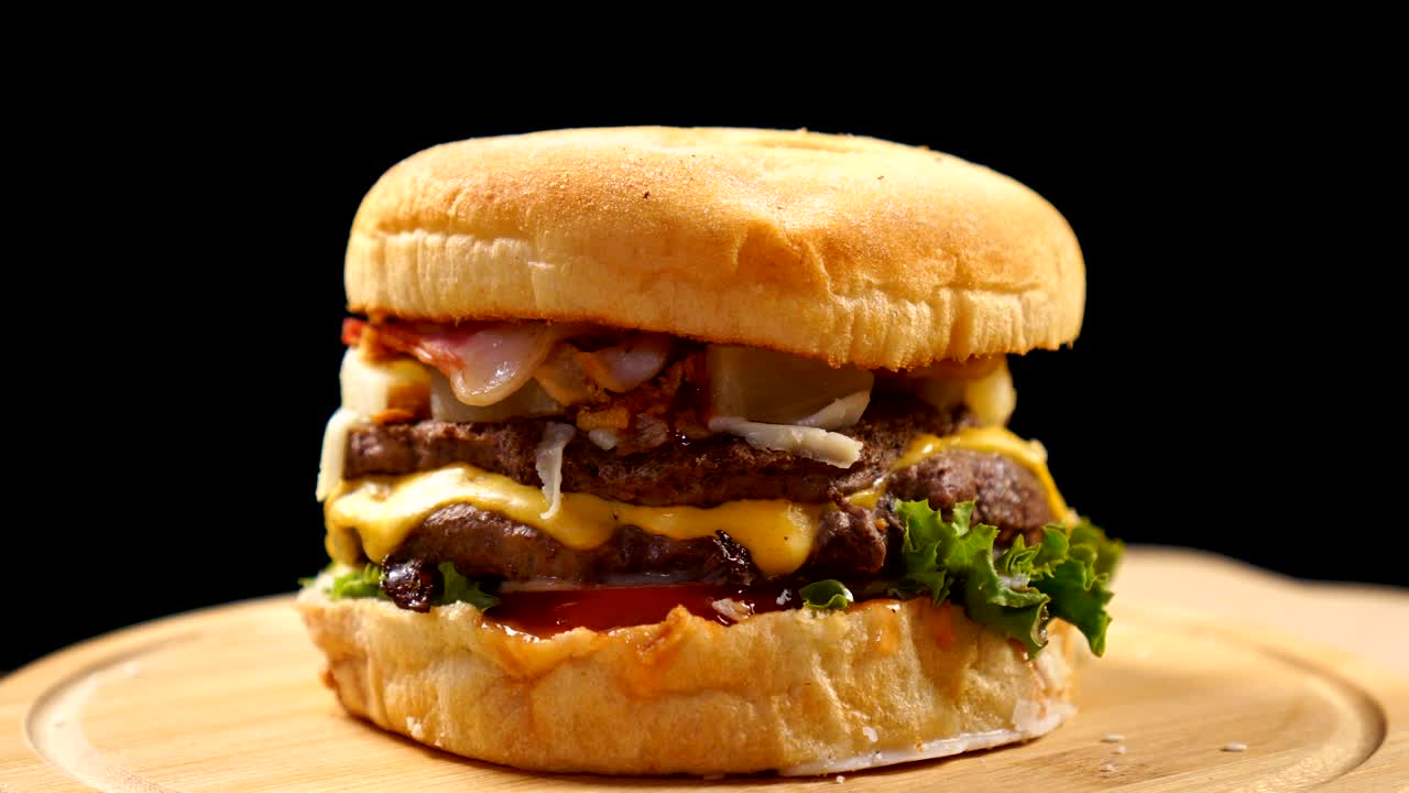 una hamburguesa fresca y jugosa girando sobre un fondo negro.