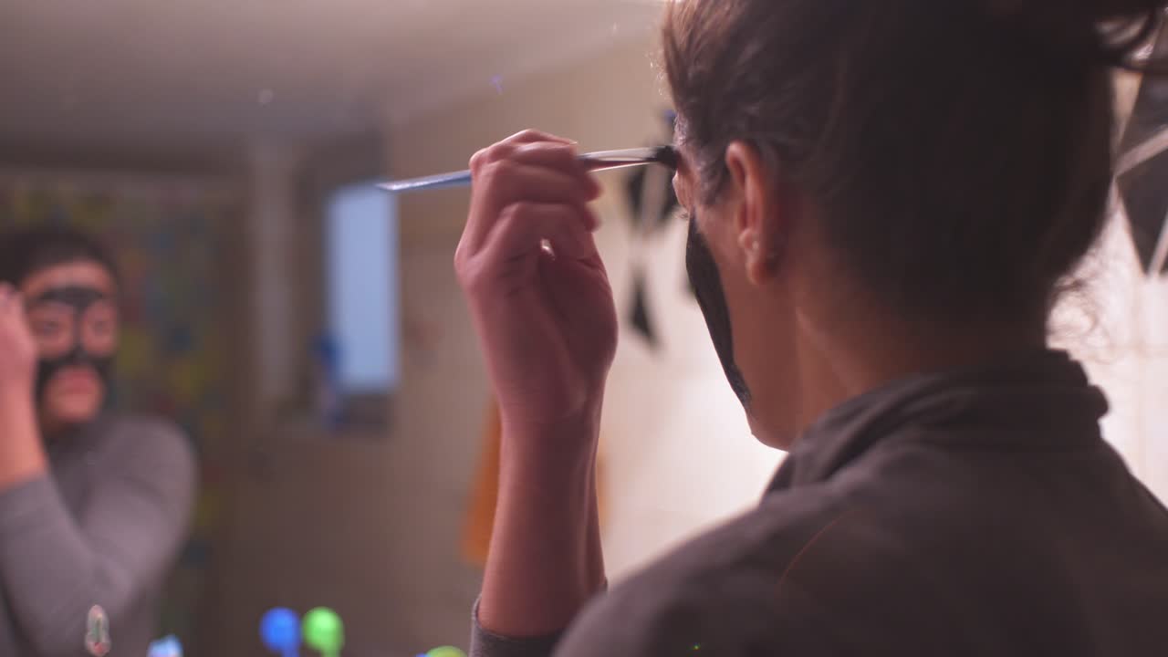 joven mujer caucásica aplicando mascarilla de belleza negra en su cara en casa