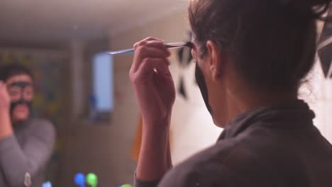 young caucasian woman applying black beauty face mask on her face at home